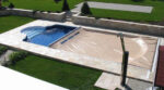 Rectangular in-ground swimming pool with rounded spa, one half filled with blue water and the other half covered by a beige cover, set in stone patio surrounded by green lawn.