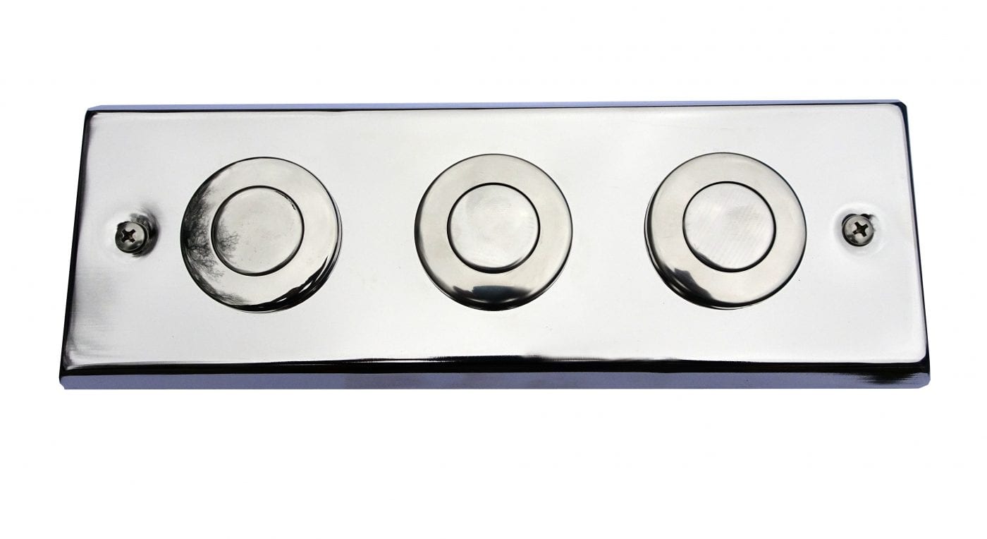 Pneumatic Button x 3 Concrete Polished chrome rectangular plate holding three circular push buttons and two crosshead screws, mounted flat against a white background and reflecting faint surrounding shapes.