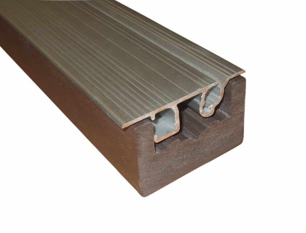 flush-track-and-receptor-1400x1067 Composite wood block supporting an aluminum stair-nosing profile; the metal strip rests fitted into a grooved channel, showing a ridged top and hollow underside, photographed against a white background.