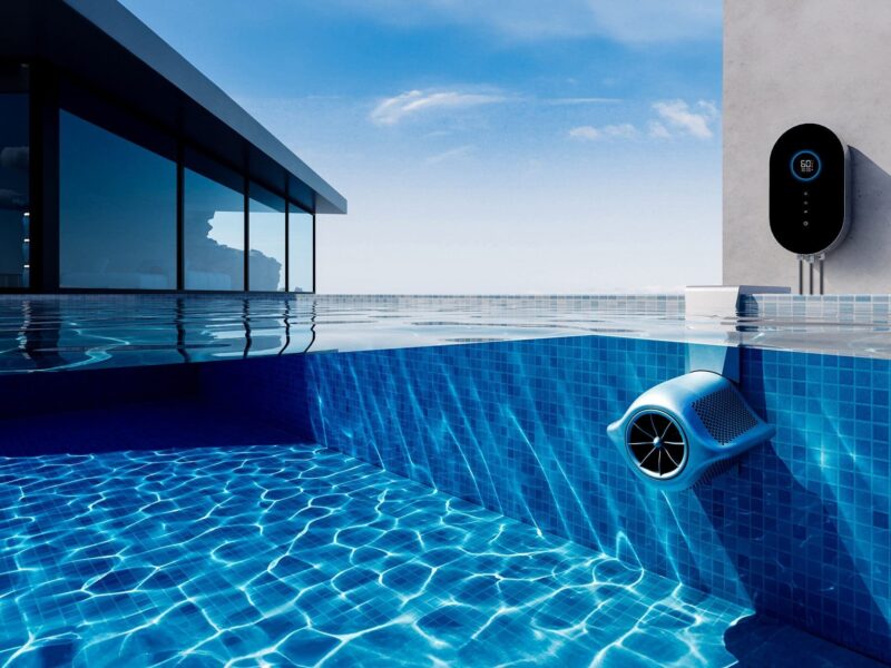 Oval wall-mounted pool control displays 60°F while a blue underwater skimmer circulates water along the tiled pool wall beside a modern glass-walled house under a clear sky.